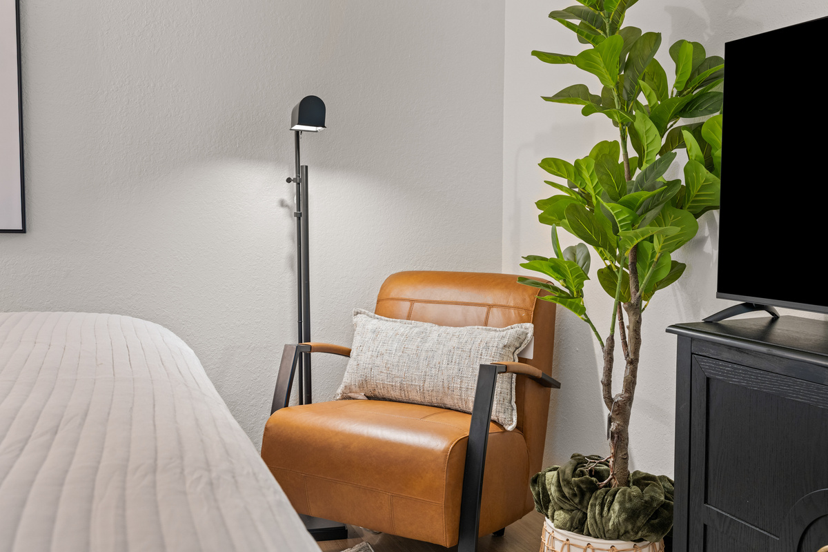 The guest bedroom includes a comfortable reading chair and its own television.