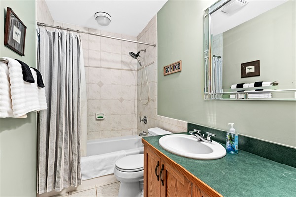 Convenient basement bathroom located just off the living room, featuring a shower-tub combo. A functional and comfortable space for guests to freshen up after a day of exploring.