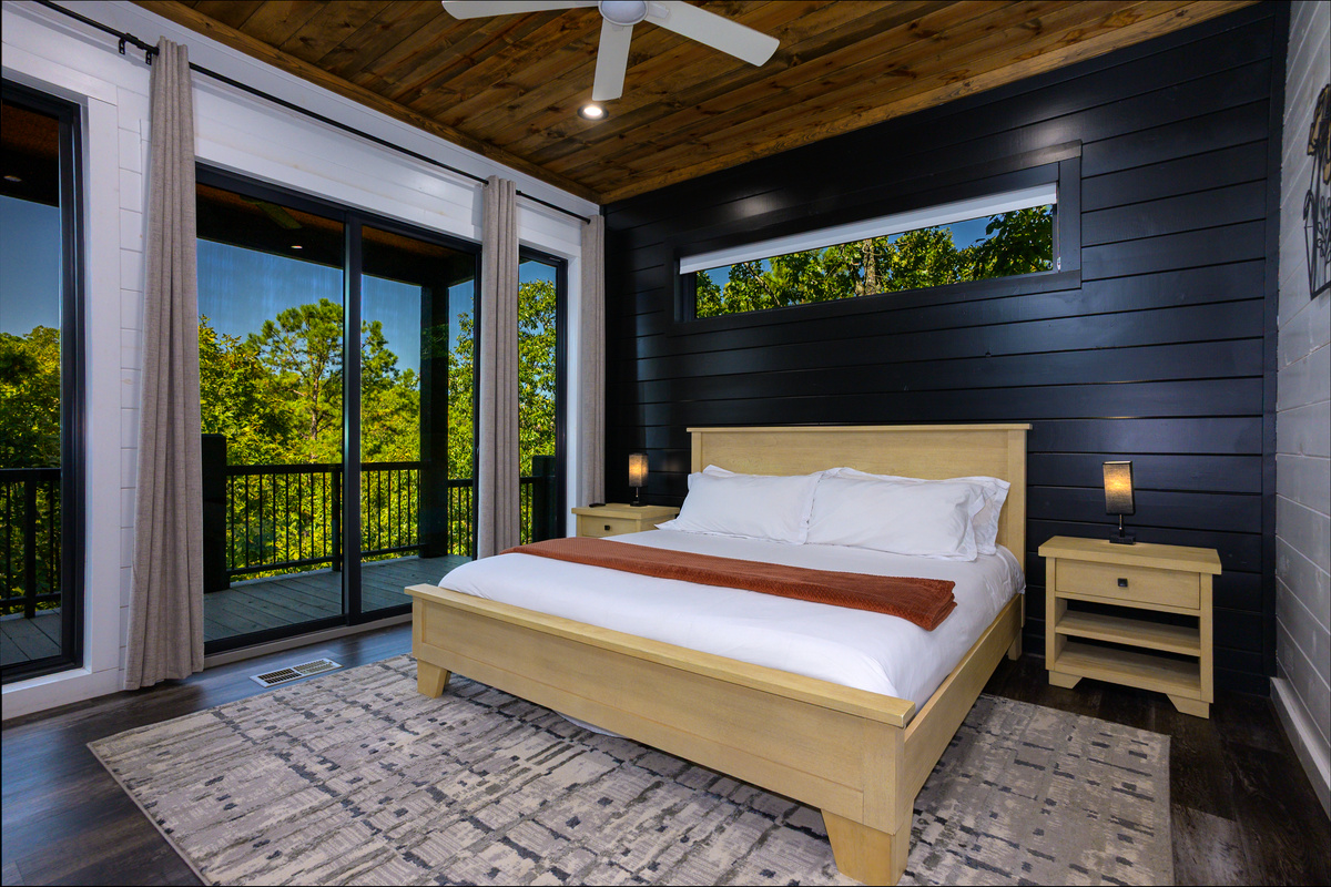 Bedroom designed with an inviting decor, cozy bedding and large windows with Wraparound deck and peaceful forest views