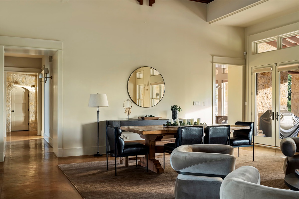 A stylish round mirror reflects the elegant dining area and spacious living room.