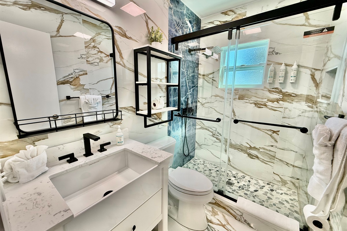 Enjoy the upscale vibe of this fully remodeled bathroom, complete with a custom vanity, matte black hardware, and a spacious tiled shower.