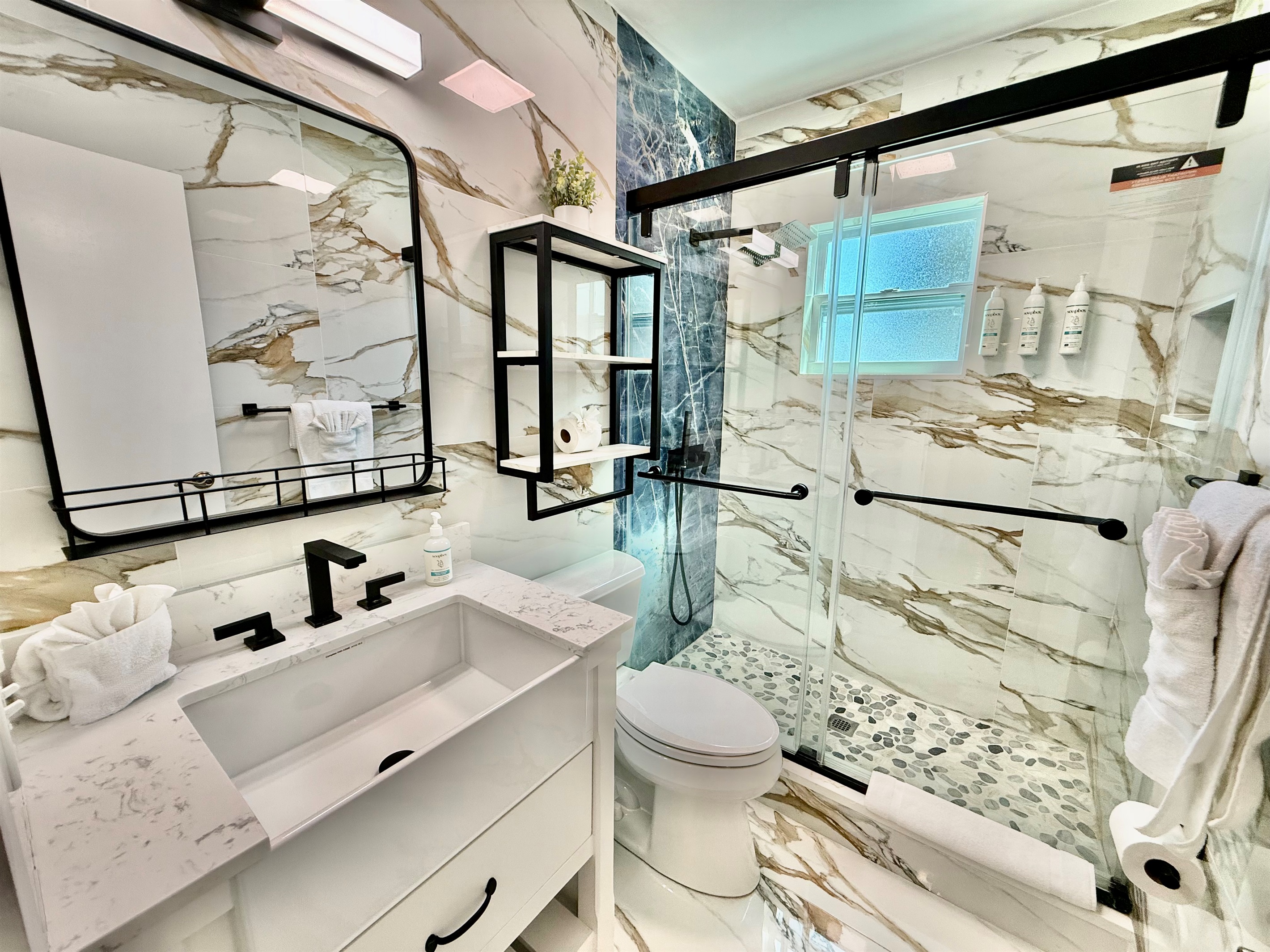 Enjoy the upscale vibe of this fully remodeled bathroom, complete with a custom vanity, matte black hardware, and a spacious tiled shower.