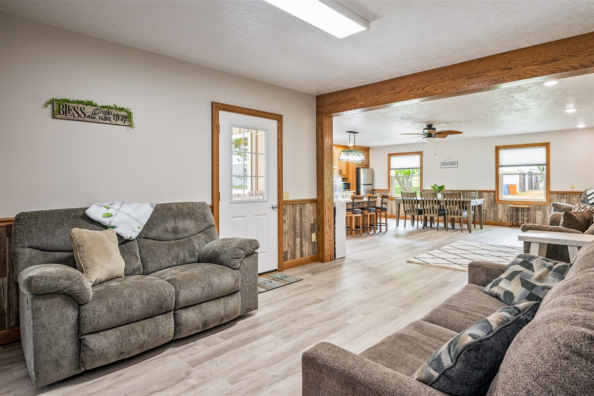 Spacious open-concept living and dining area with natural light, comfy recliners, and a seamless flow into the kitchen. Ideal for entertaining!
