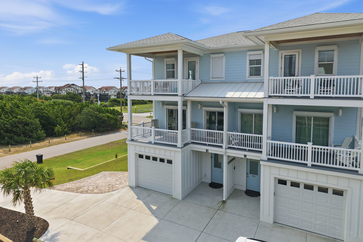 Rear aerial view displaying the expansive decks, outdoor living spaces, and peaceful coastal surroundings