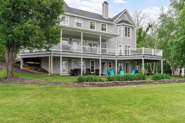 A striking lakefront home featuring multiple levels of outdoor living, distinctive architectural details, and stunning views of Saratoga Lake.