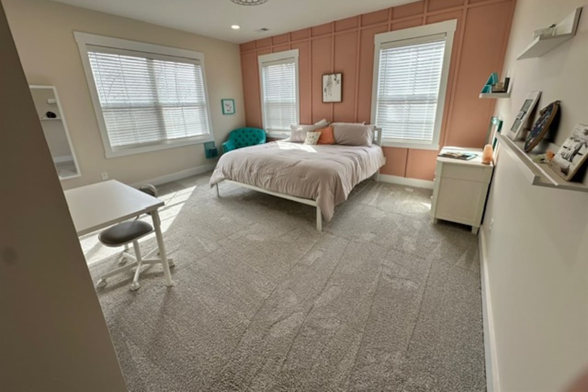 Bright and cheerful, with a super comfy chair for reading and a desk. Private sink and makeup vanity area with access to private toilet and shower rooms, which are shared with bedroom #5.