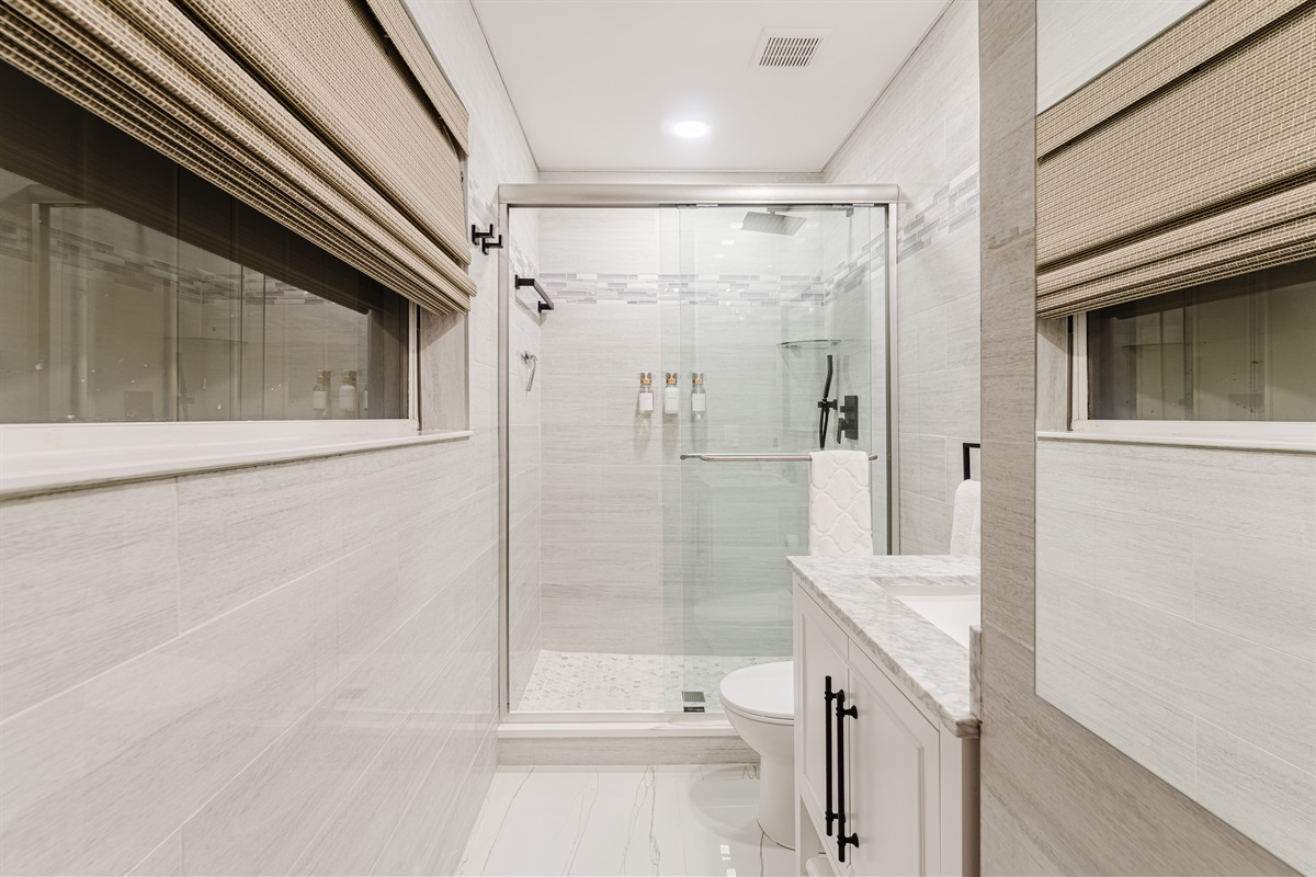 Private spa-style ensuite with a glass-enclosed walk-in shower, marble vanity, matte black fixtures, and hotel-quality finishes.