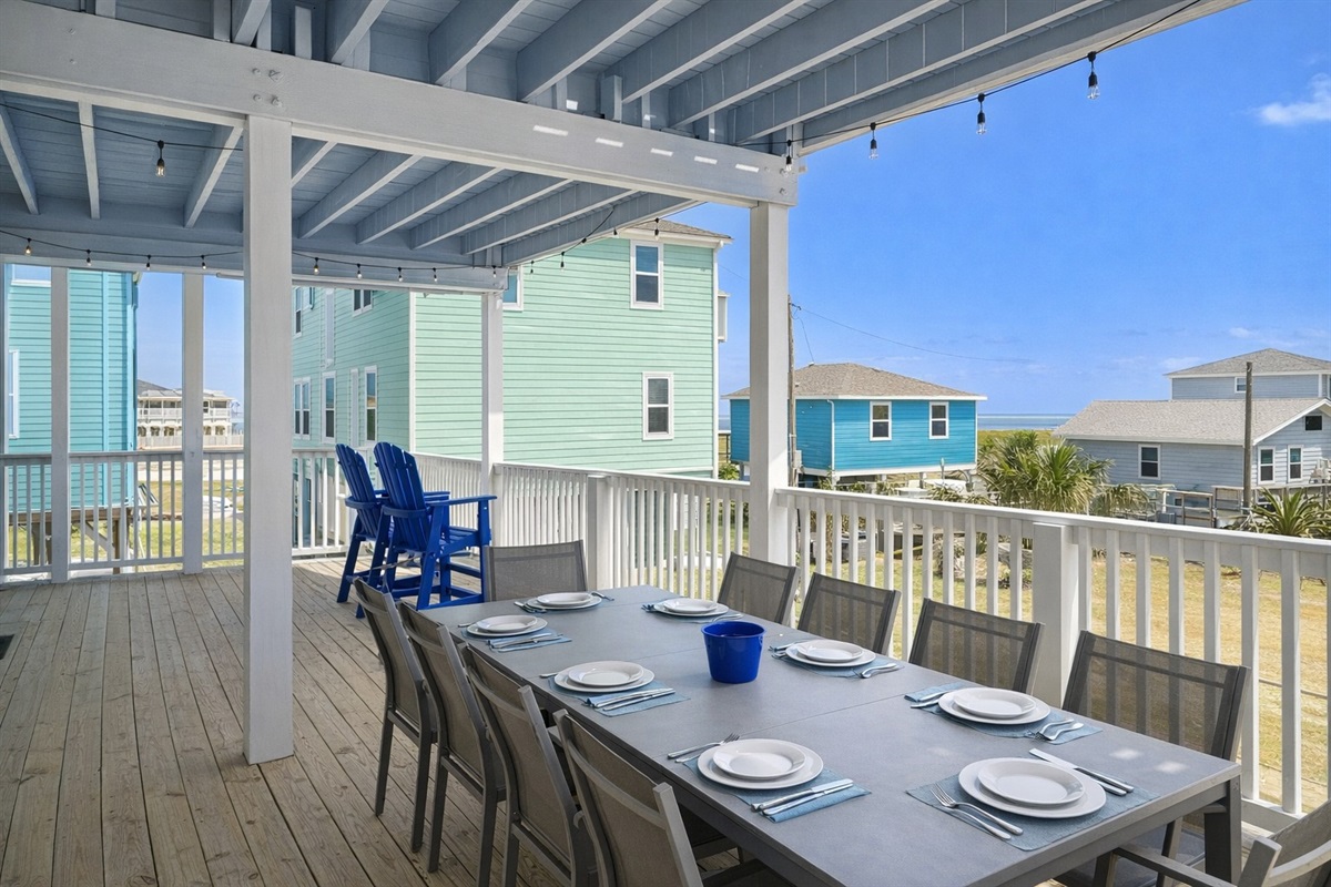 Covered Outdoor Dining (Main Level Deck): Large table seating for group meals with coastal views.