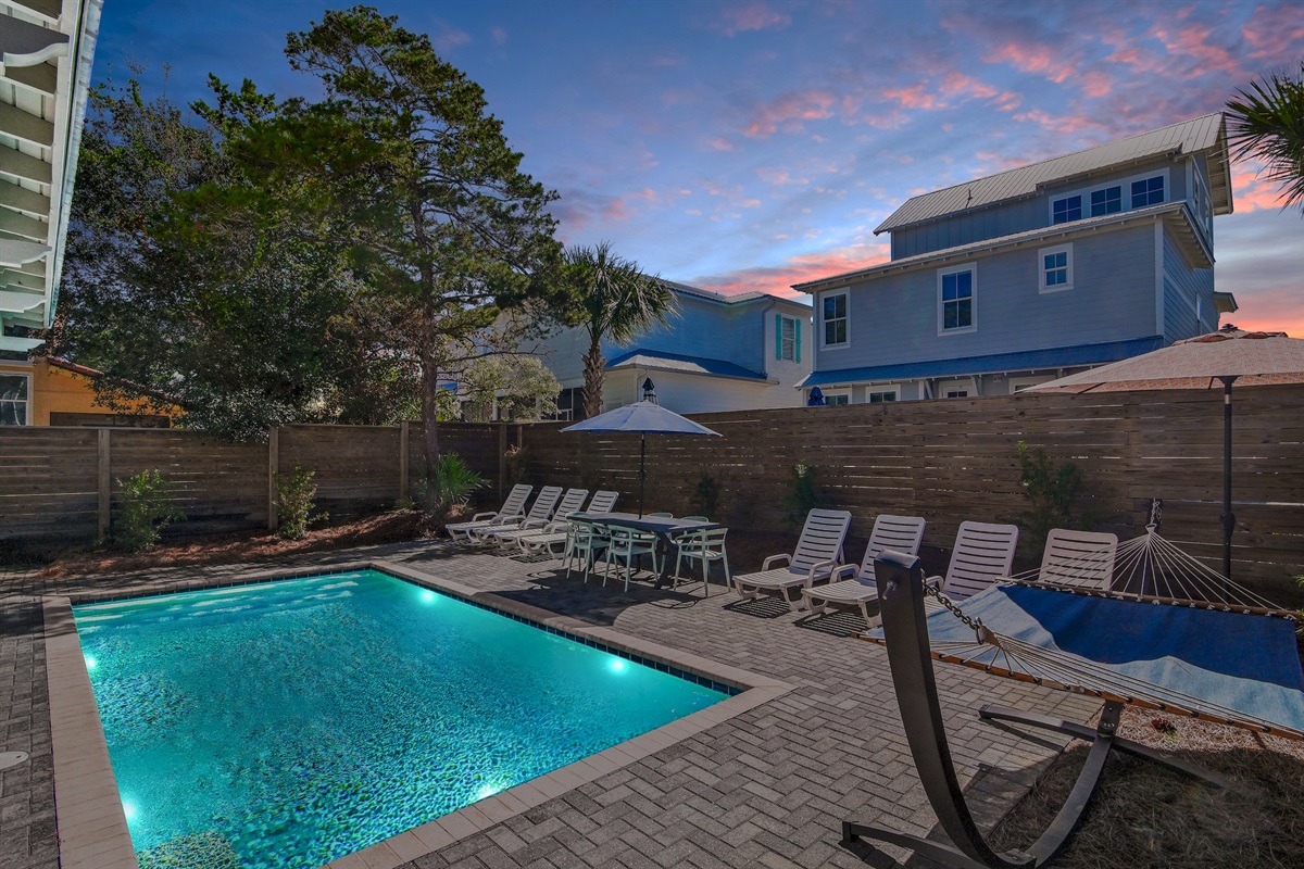 Beautiful backyard with pool, hammocks, loungers, umbrellas, and outdoor grill.