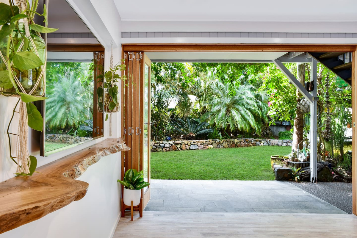 Natural timber finishes, open bi-fold doors and dense tropical greenery give this garden-facing space at Aaron's Beachside Boat House plenty of distinctive coastal character.