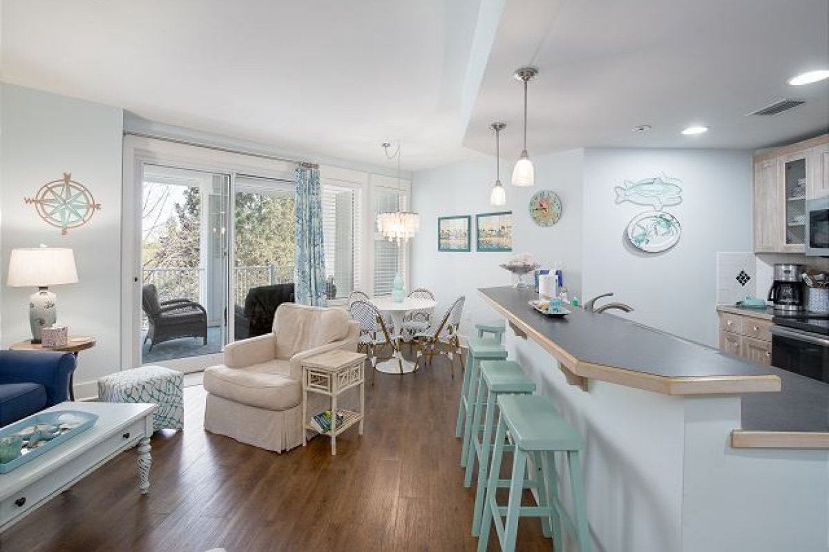 Open living area with breakfast bar seating, dining nook and sliding doors to the balcony
