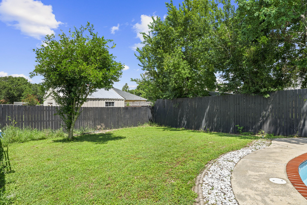 Plenty of green space for kids or pets to play, tucked behind a tall privacy fence.