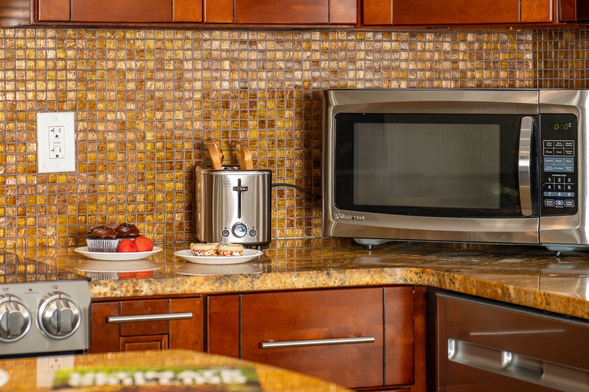 A golden mosaic backsplash brings texture and sparkle to the space, tying together the cabinetry and granite countertops.