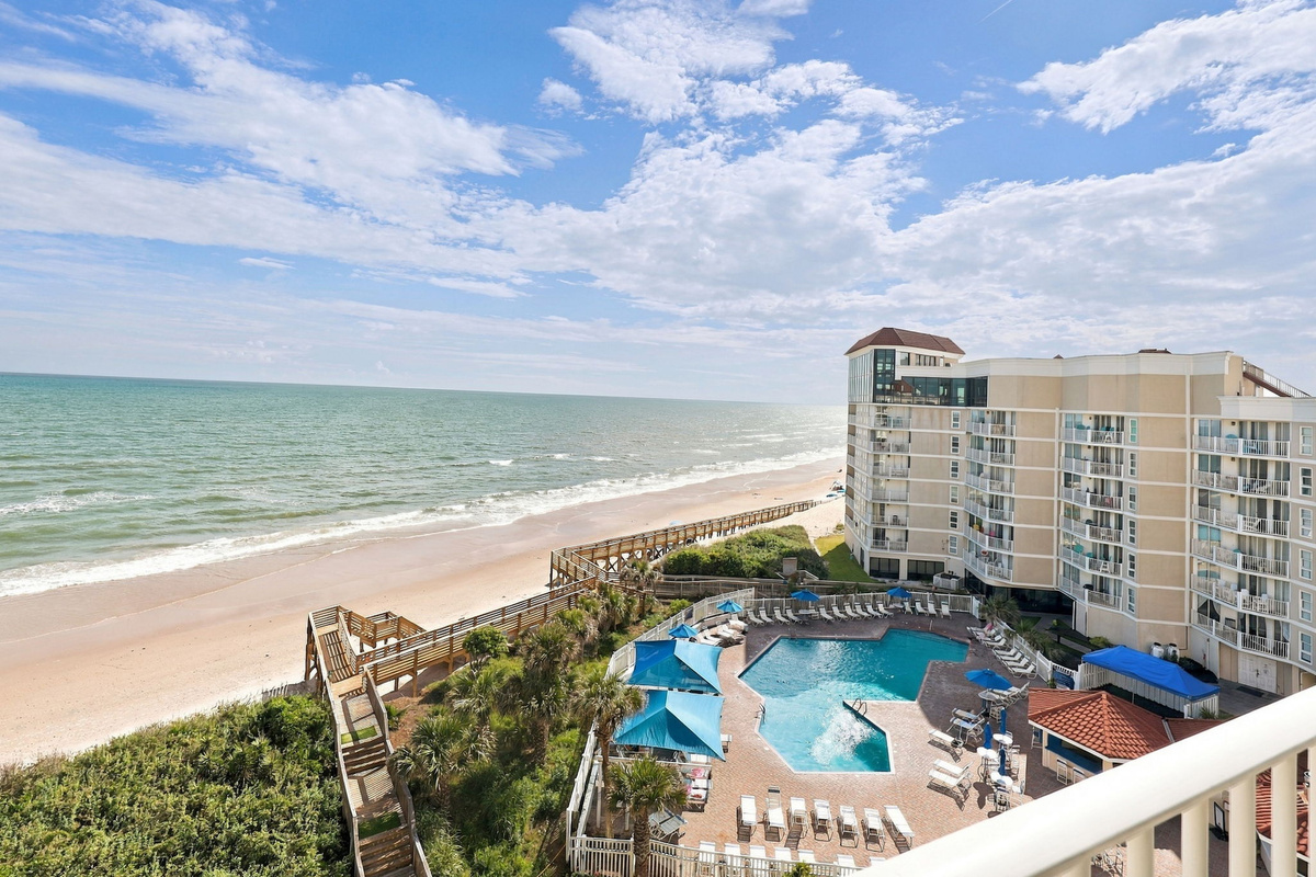 Stunning beachfront views of the ocean, sandy shore, and sparkling resort pool right from your balcony.