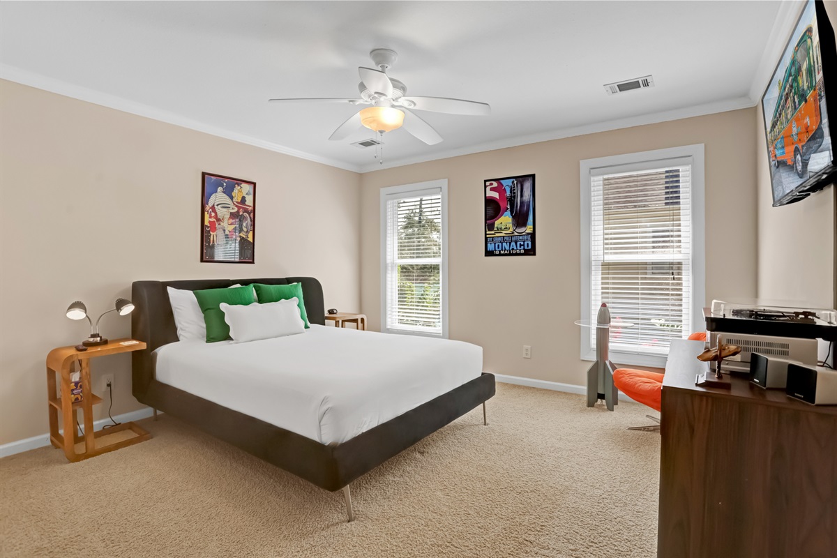 Bright and stylish bedroom featuring a modern platform bed, playful retro accents, and plenty of natural light from large windows.