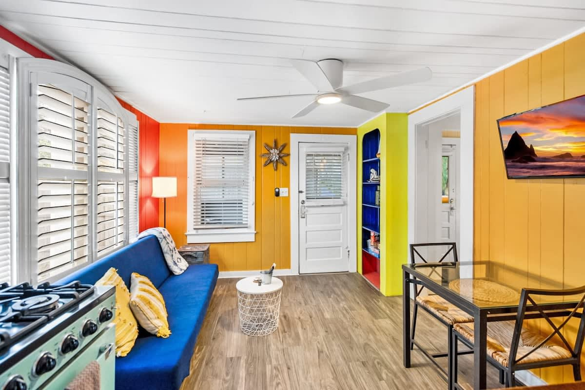 Sofa, dining table and kitchen all in one bright room. There is no formal living room in this cottage, which is worth knowing before you book, but the open layout means everyone ends up together anyway.
