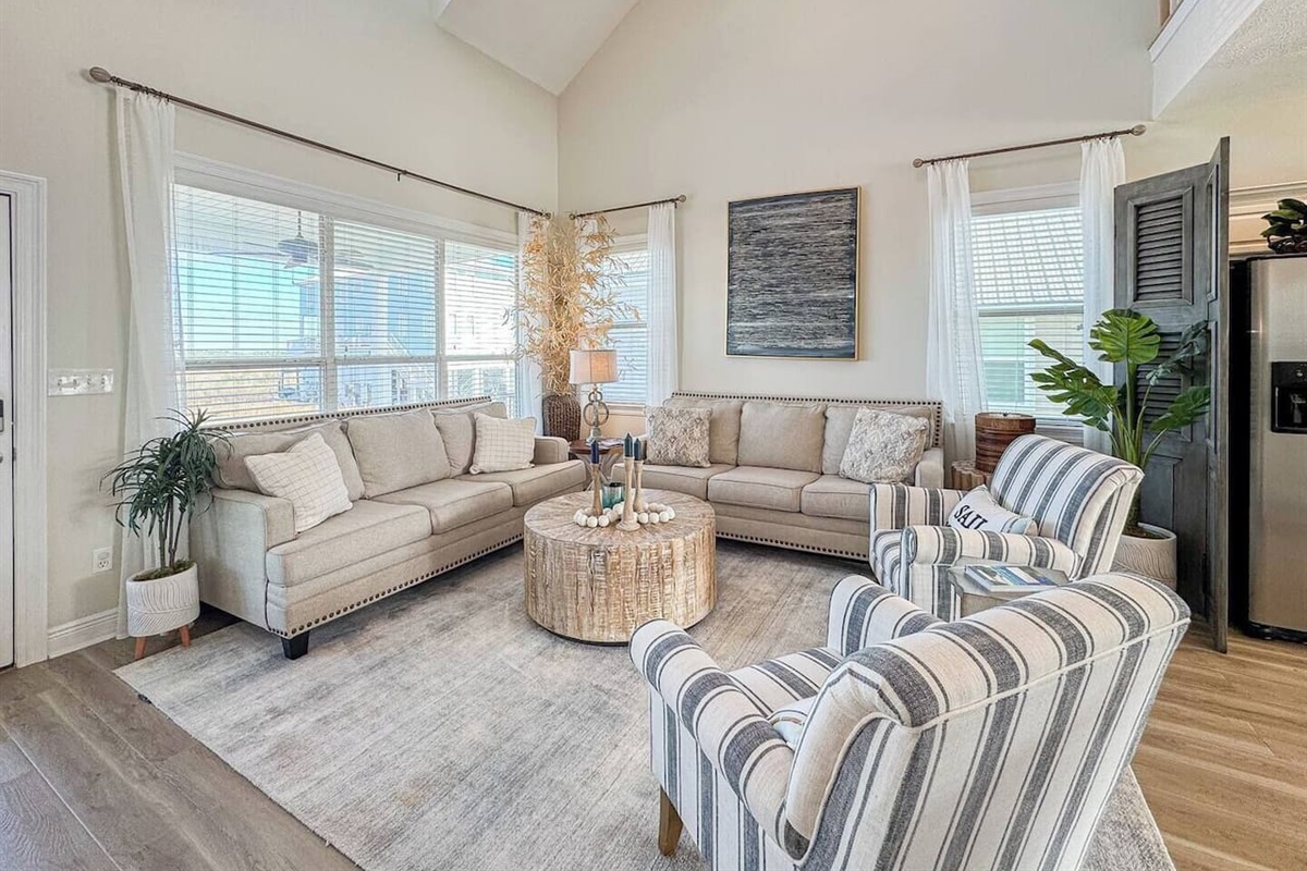 Light-filled living area with comfortable seating, coastal accents, and an open layout that flows into the kitchen—perfect for relaxing together.