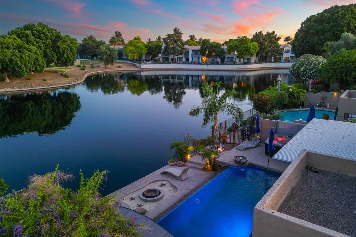 The fire bowl flickers at the water's edge as the lake mirrors the sunset sky — settle into the lakeside patio and let the evening unfold at its own pace.