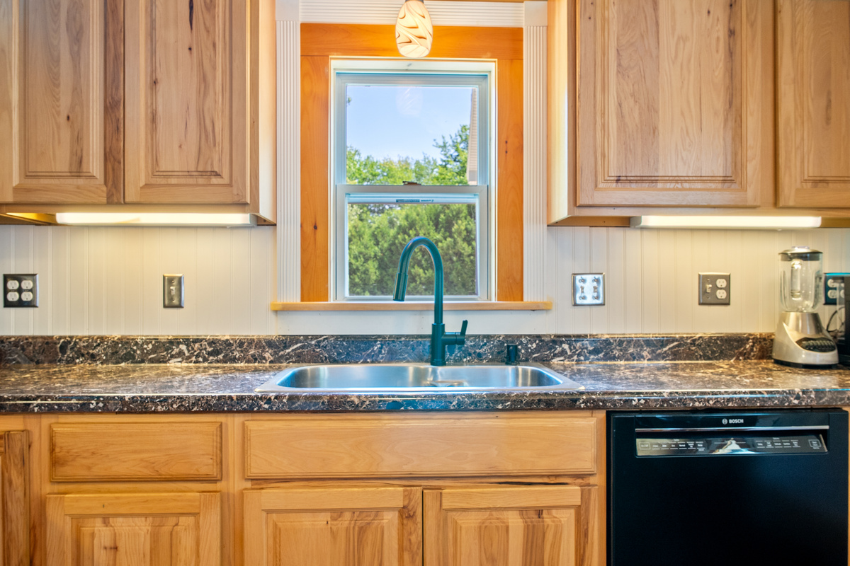 Clean up easily using the premium Bosch dishwasher integrated below the kitchen counter. This wider perspective reveals the abundant solid wood cabinetry storage, under-cabinet task lighting, and a countertop blender for your morning smoothies.