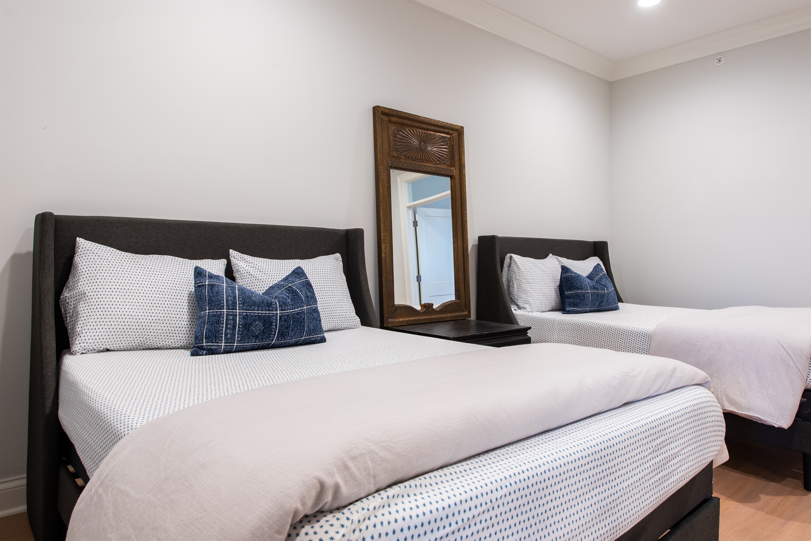 Open Loft/Additional sleep setup featuring full beds with coordinated bedding in soft blues and whites, complemented by a central nightstand with a decorative mirror, creating a harmonious and balanced space for rest and relaxation.