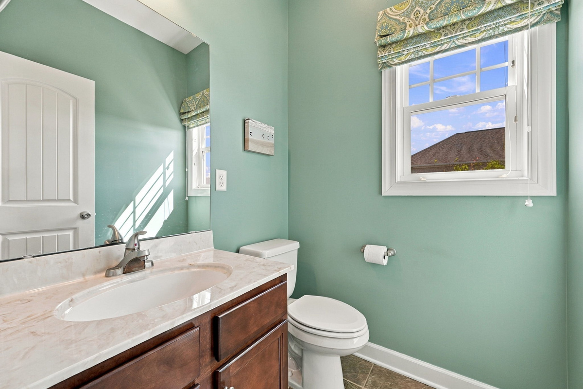 Bright and inviting bathroom featuring a spacious vanity, natural light, and coastal-inspired finishes