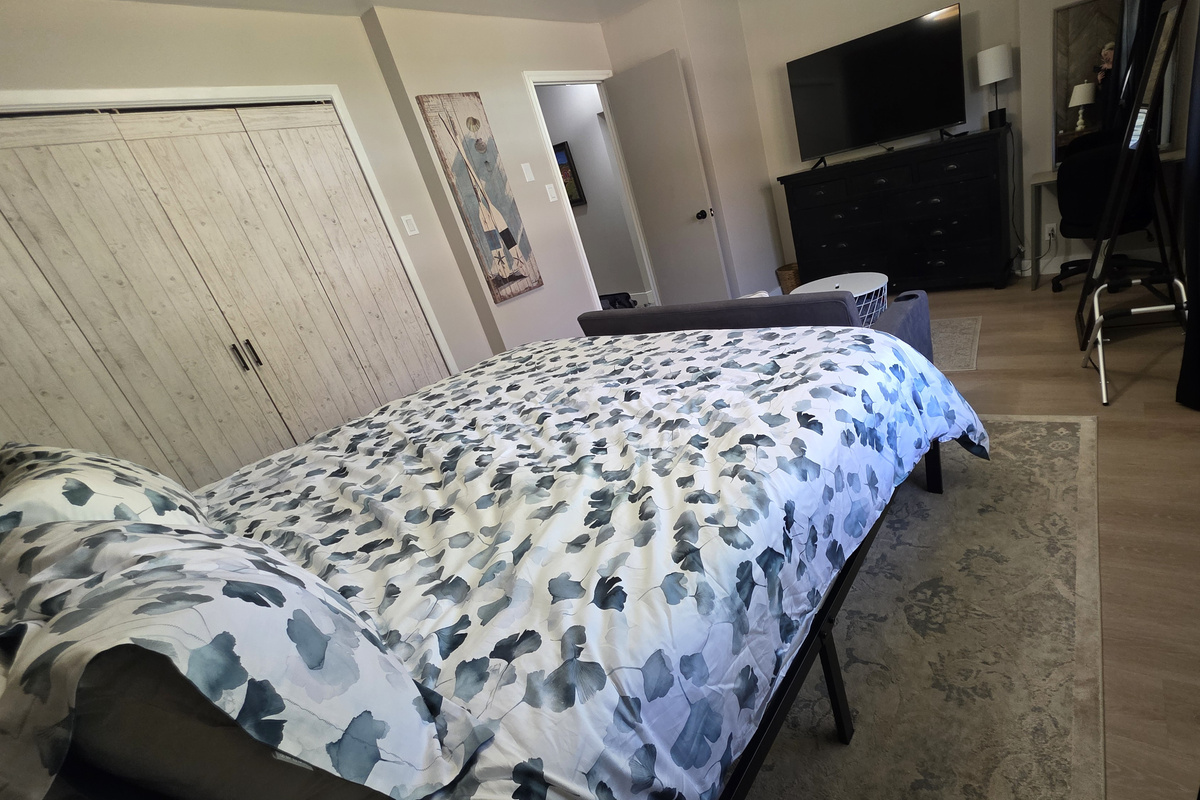 Your comfortable escape: primary bedroom with TV, pull-down couch, desk, soft carpet, dresser, closet, USB lamps, and cozy robes.