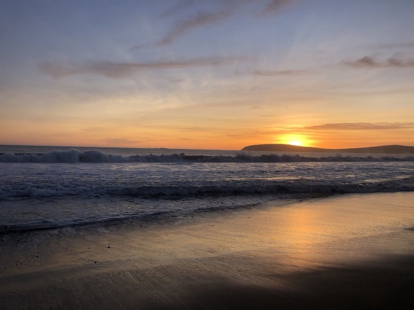 Sunset above the ocean and wet sand