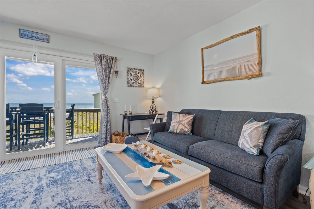 Bright coastal living space with direct balcony access, ocean views, and a cozy spot to unwind after the beach
