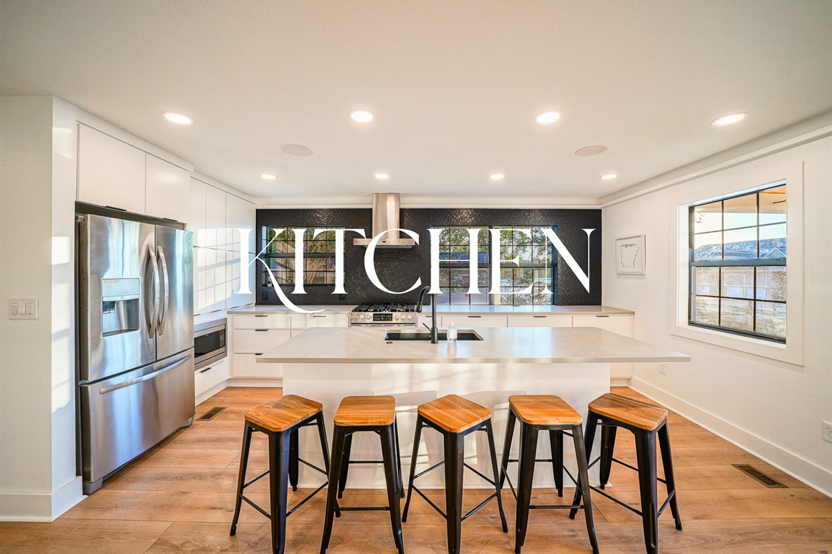 This stunning kitchen features a massive island, black tile backsplash, and chef-ready appliances — ideal for hosting in style.