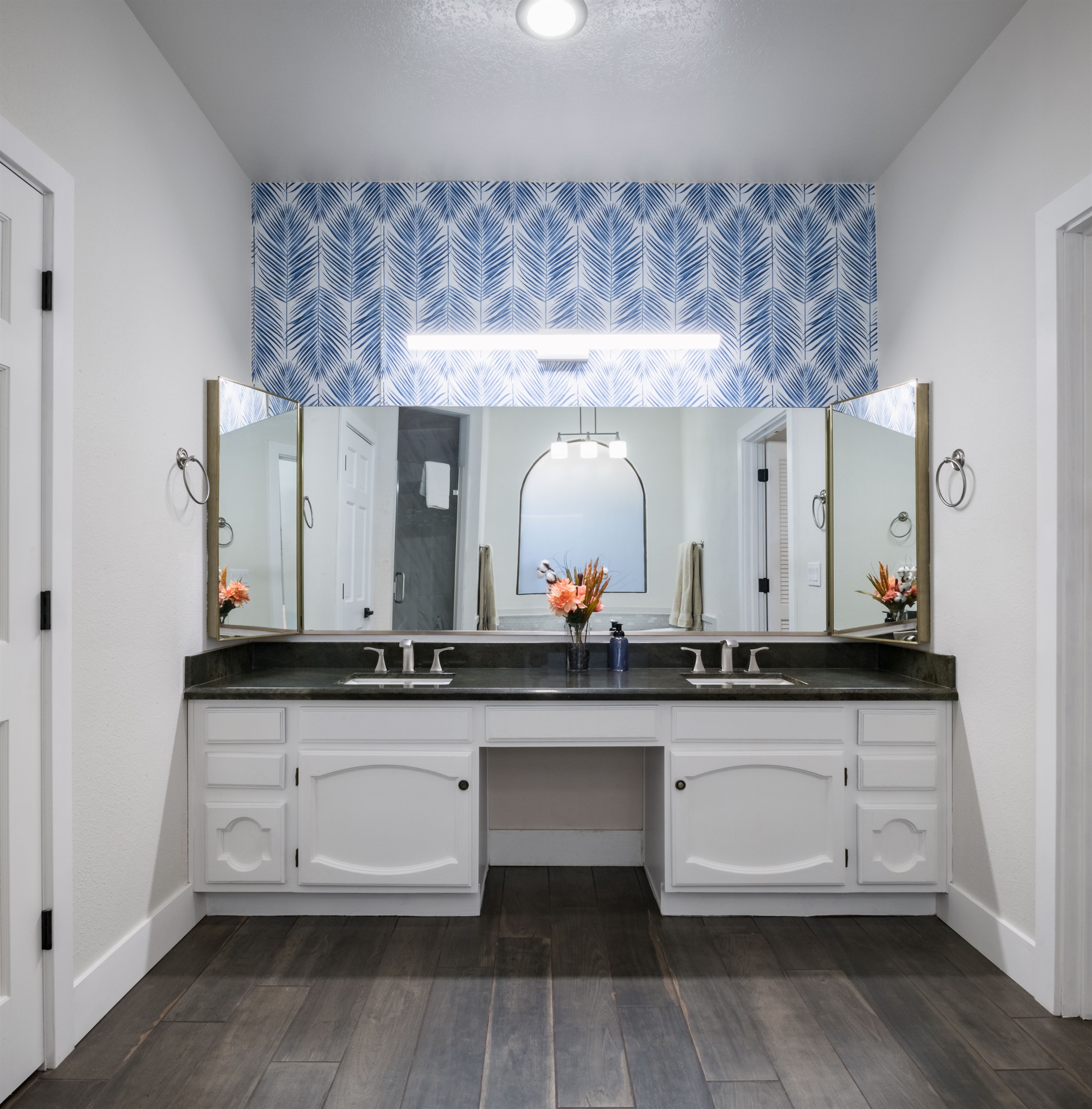 Treat yourself to a stylish bathroom sanctuary with bold wallpaper, dual sinks, and a deep soaking tub perfect for winding down.