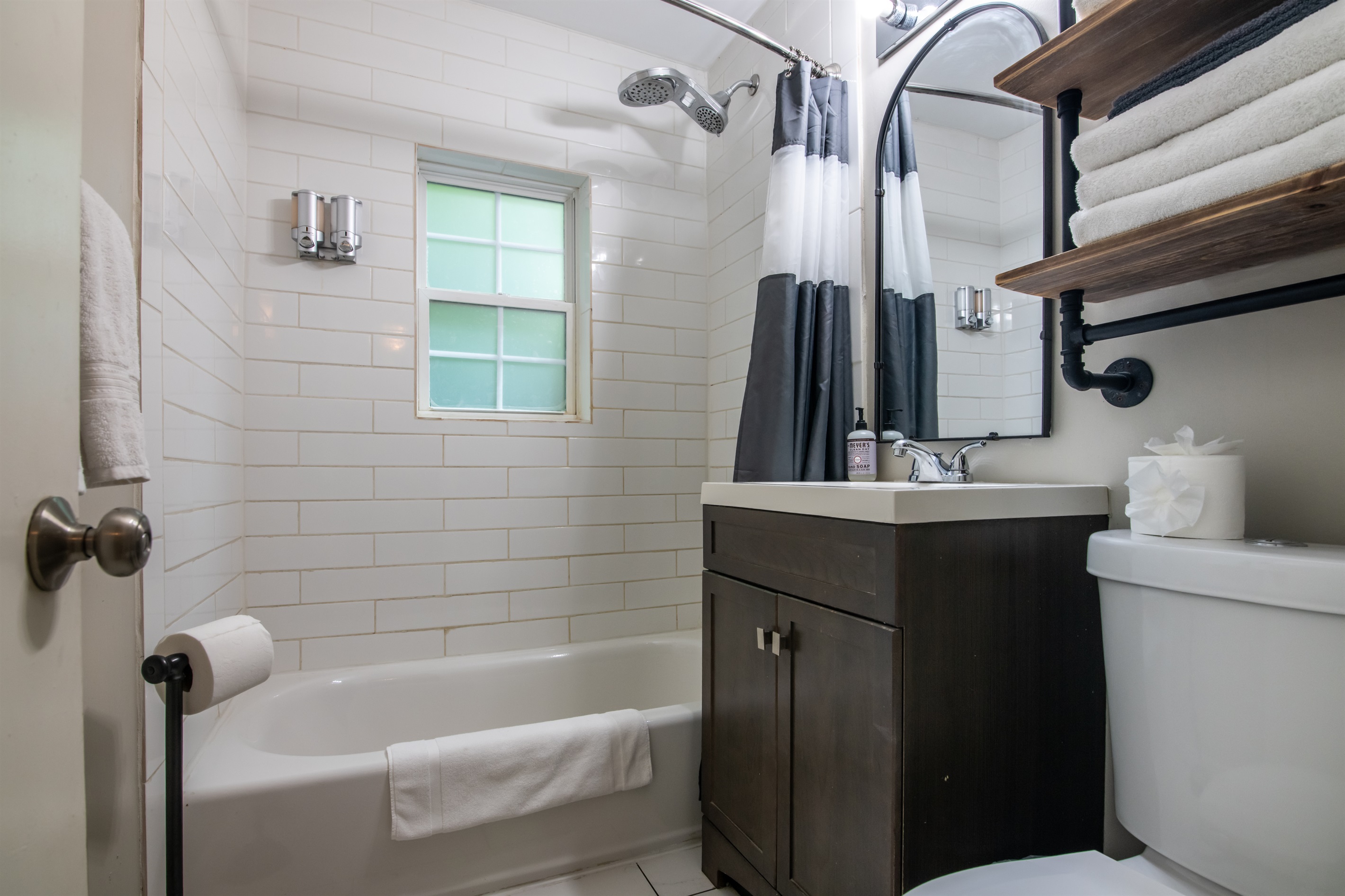Modern bathroom with subway tile, bathtub/shower combo, and natural light.
