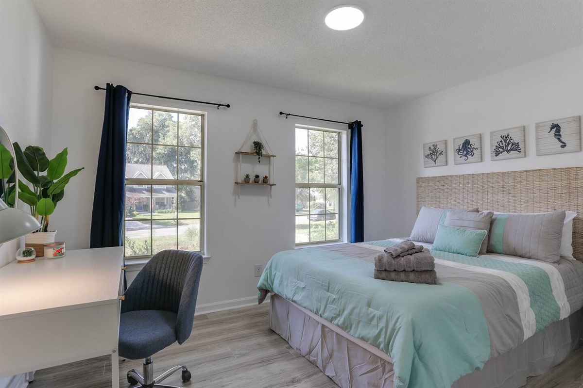 Bright and inviting, the second bedroom features a cozy queen bed, a convenient desk, and large windows that fill the space with natural sunlight.