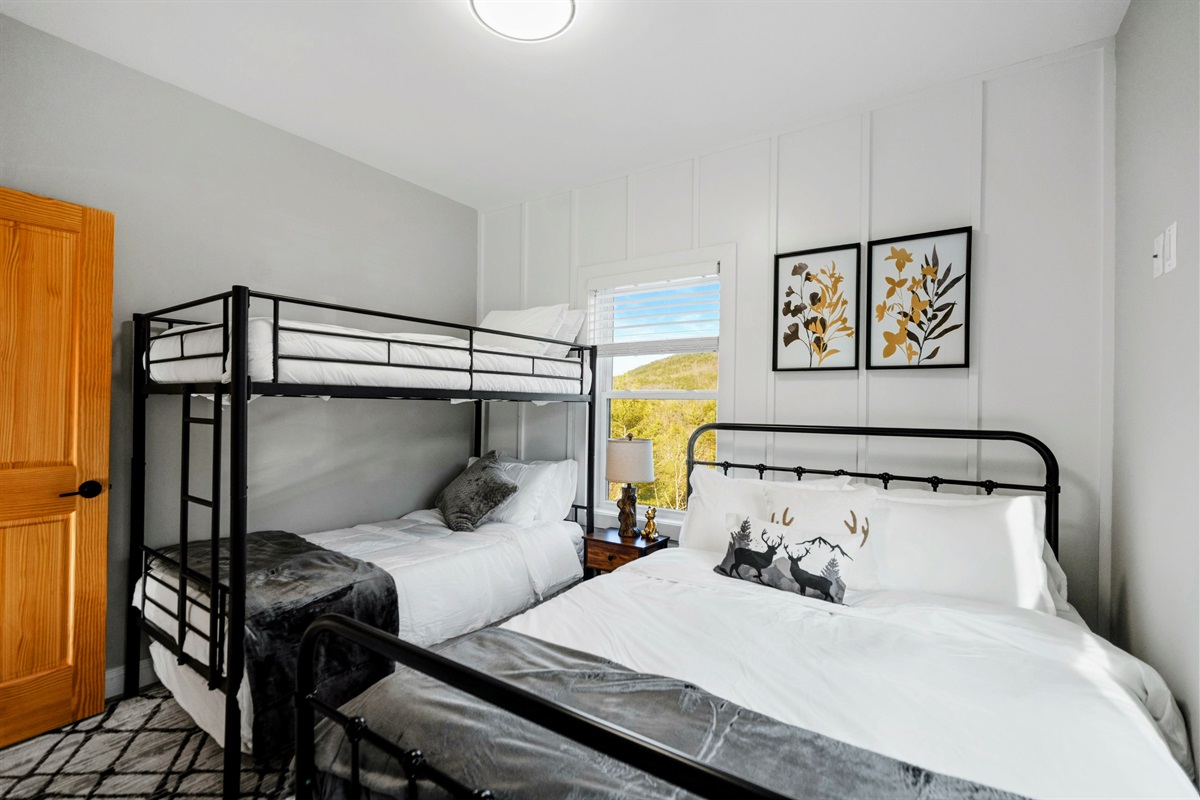 Mountain Sleepover – Gather the family in this inviting bedroom, featuring plush beds and views of the surrounding forested hills.
