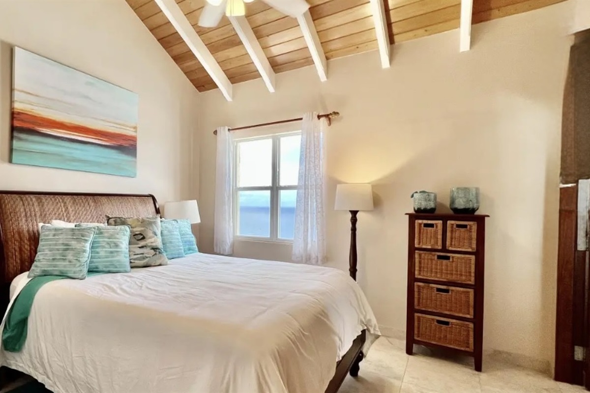 Guest bedroom with vaulted ceilings and ocean view—wake up to blue water every day.