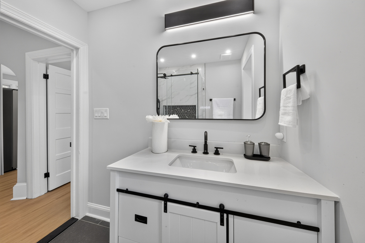 Sleek vanity with matte black fixtures, bright lighting, and provided fresh towel sets.
