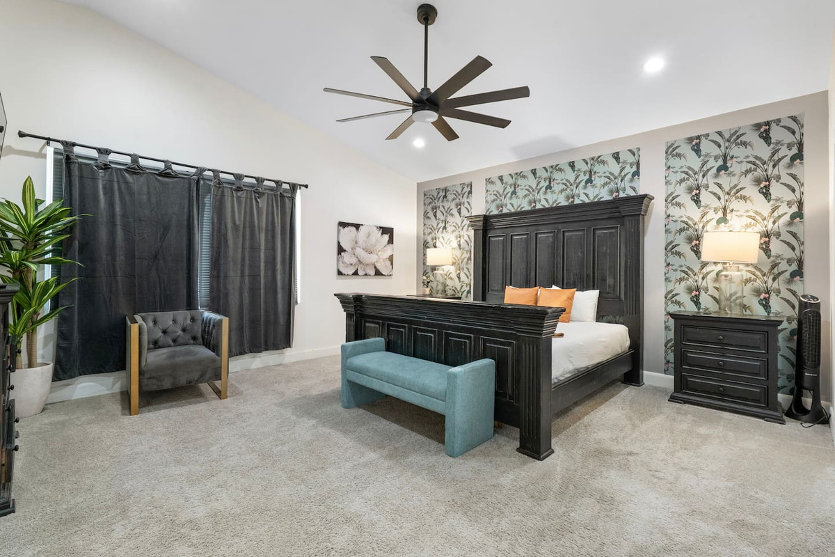 Luxe bedroom with statement black bed frame, botanical wallpaper, and spa-like seating area.