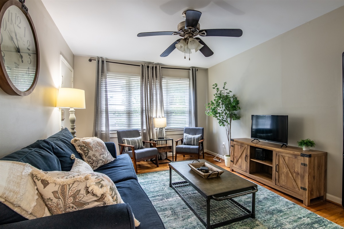 Inviting living room with plush seating, large windows, and ceiling fan—perfect for lounging or catching up on your favorite shows.