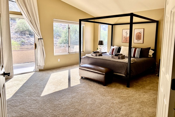 Primary bedroom with ensuite bathroom, Smart TV, walk in closet, private balcony, ceiling fan, linens and remote workstation