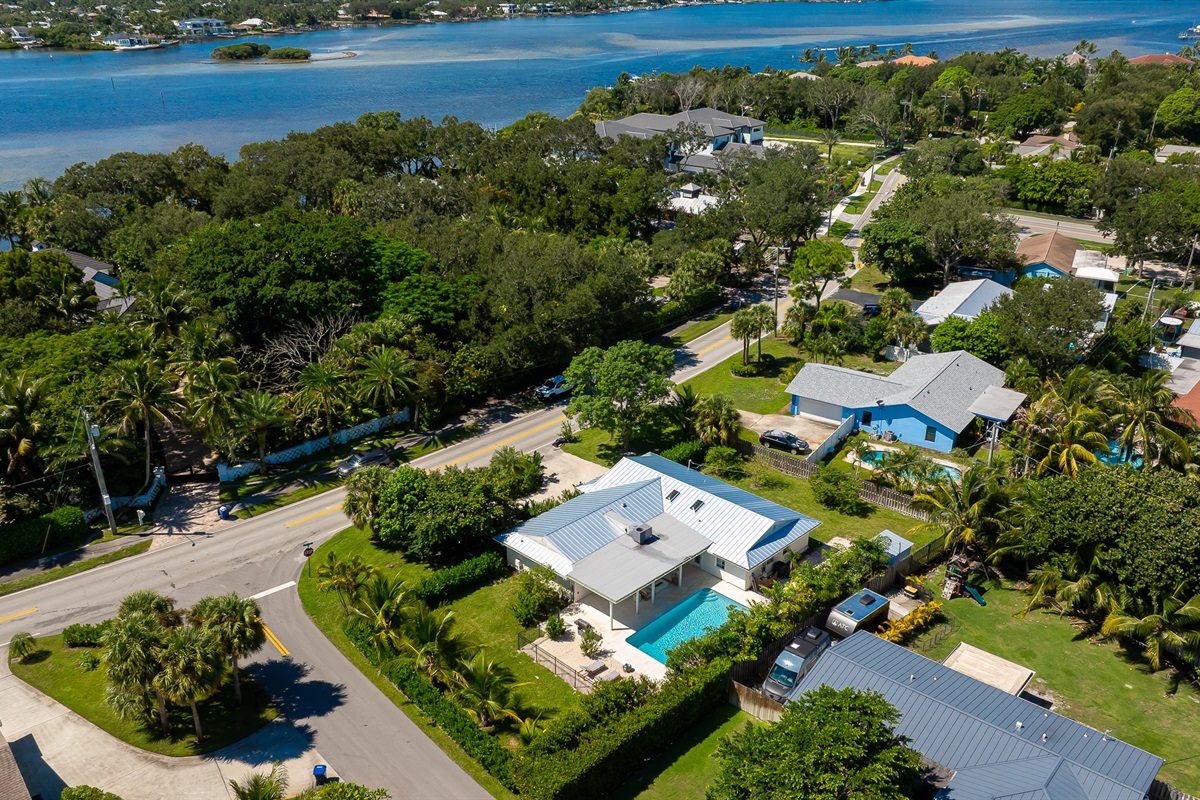 A stunning aerial view captures this luxury coastal retreat with a sparkling pool, manicured lawns, and lush tropical landscaping - offering the perfect blend of privacy, sophistication, and resort-style living just minutes from the beach.