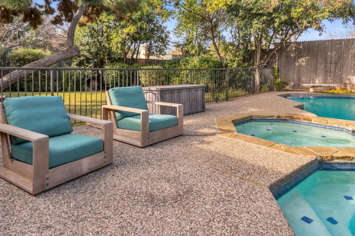 Comfortable lounge chairs positioned poolside, offering a relaxing spot to unwind, soak up the sun, or enjoy the backyard setting.