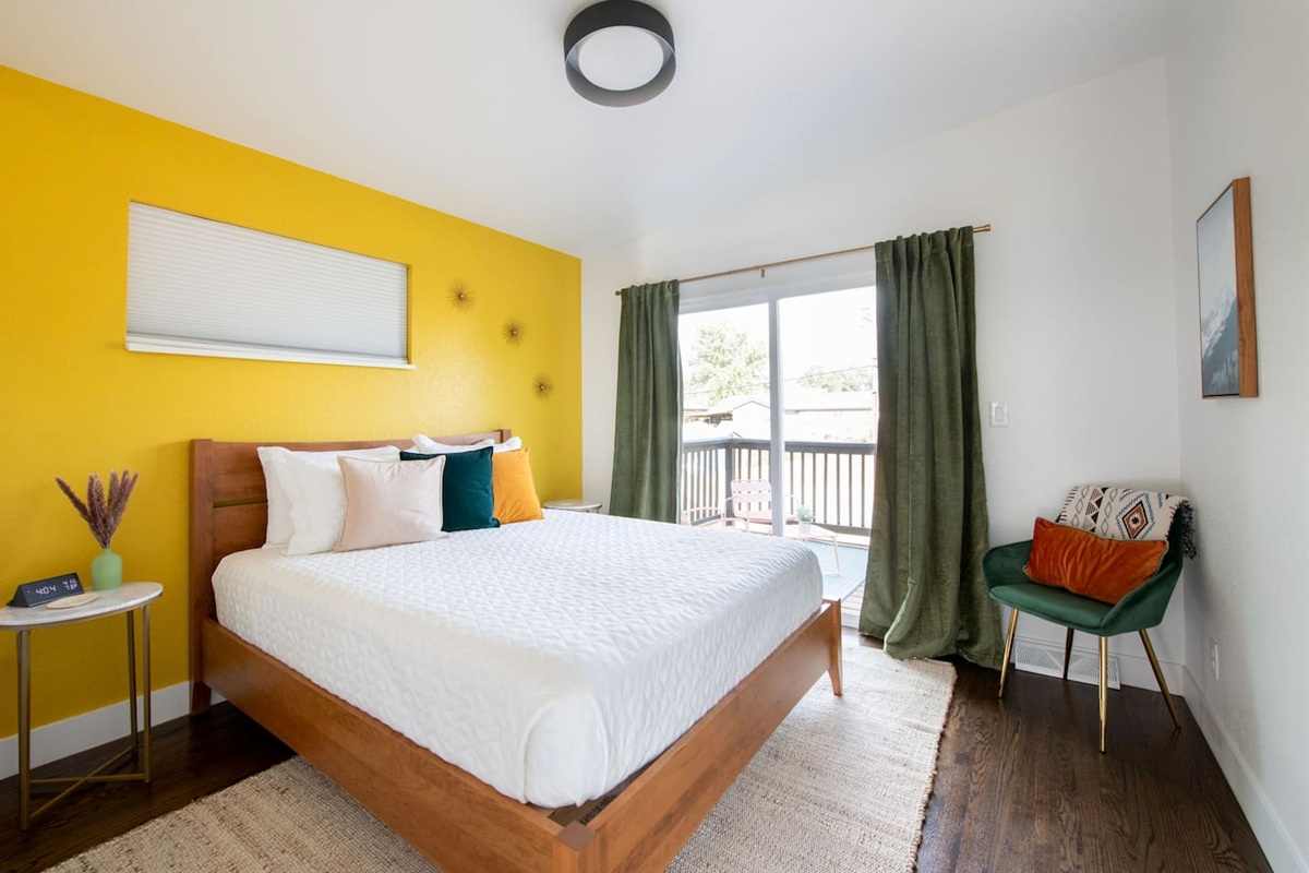 Cheerful queen bedroom with pops of color and natural light, with direct patio & bathroom access.