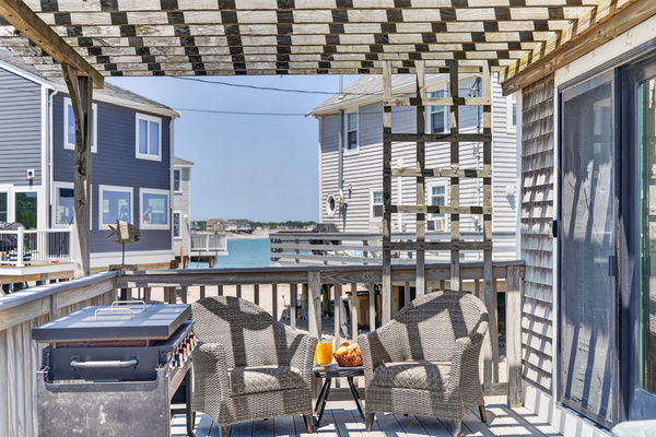Relax outdoors beneath the pergola with comfortable seating and a refreshing view toward the water.