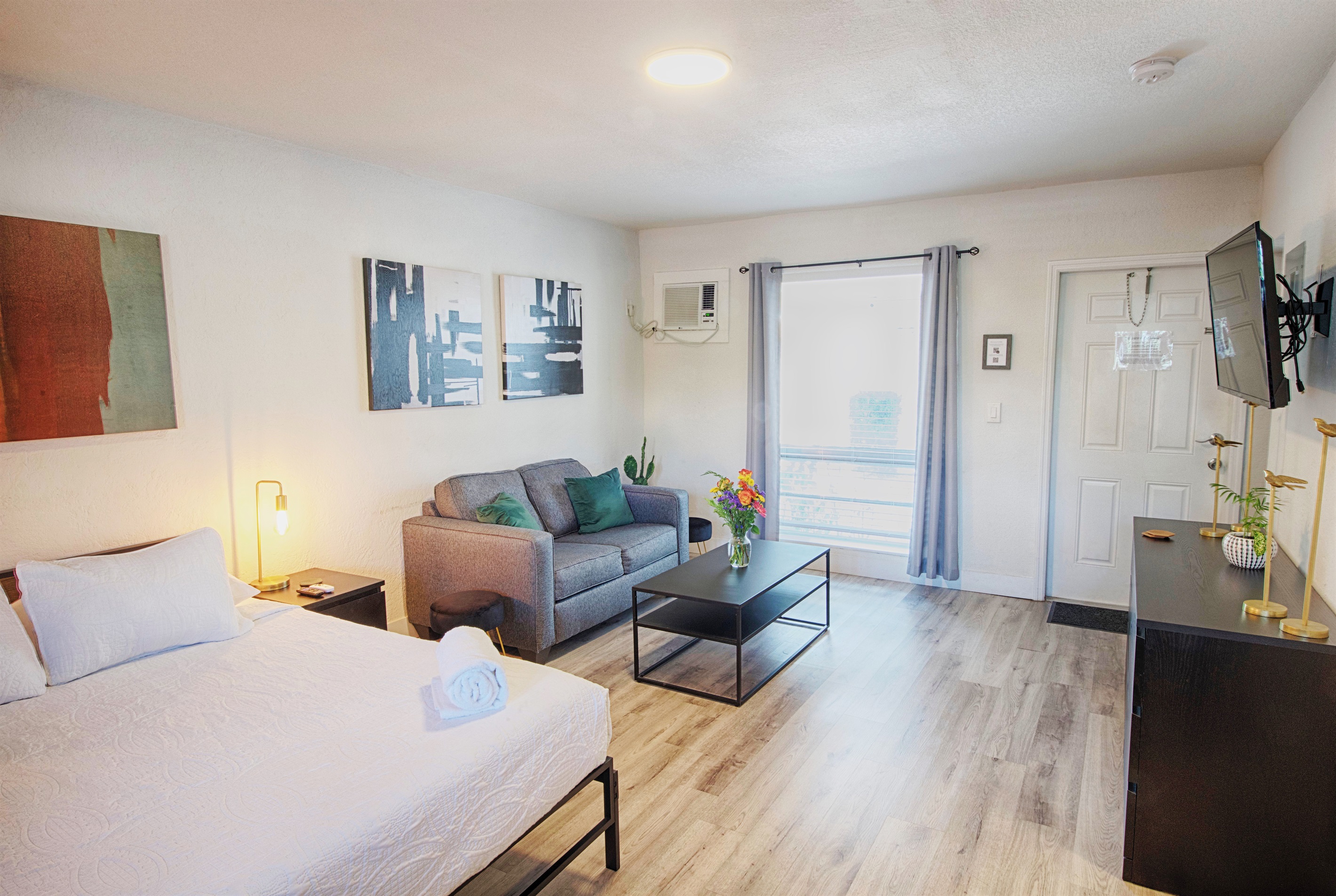 View towards apartment entry shows queen bed, love seat and coffee table.