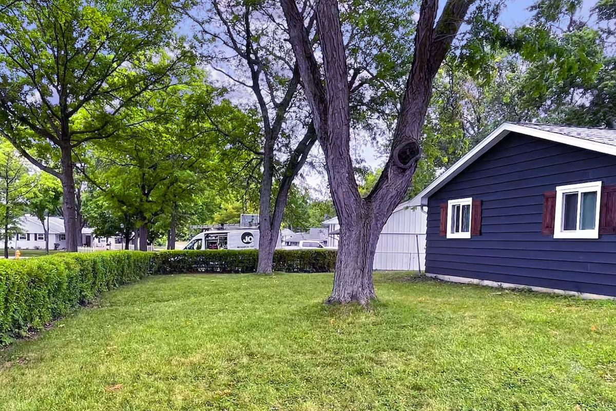 Mature shade trees and a tucked-away hedge line make this backyard feel like your own quiet retreat.