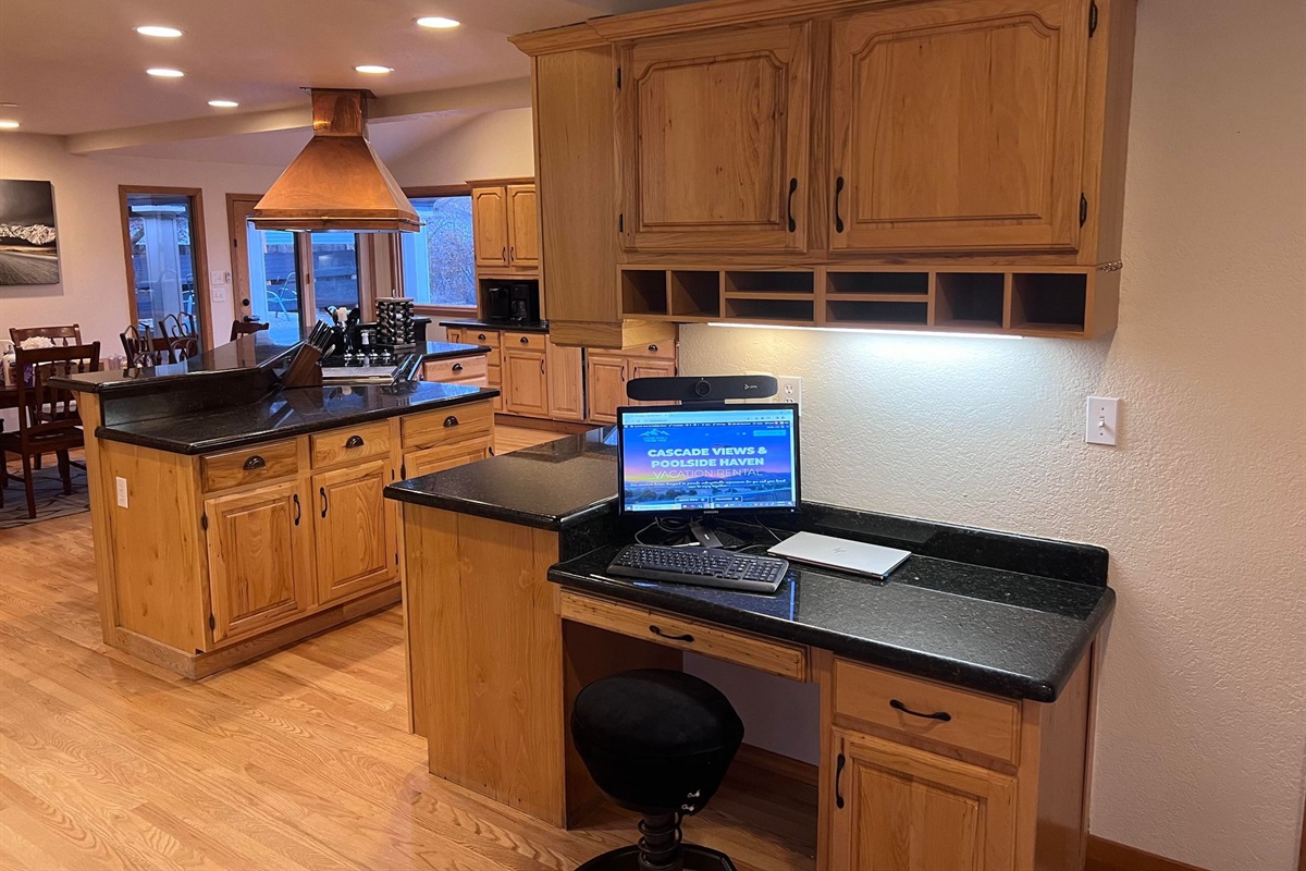 Perfect work from home desk located next to the kitchen with monitor and camera.