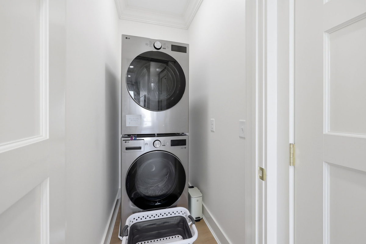 Stacked modern washer and dryer in a compact laundry closet with clean white walls and efficient built-in utility design
