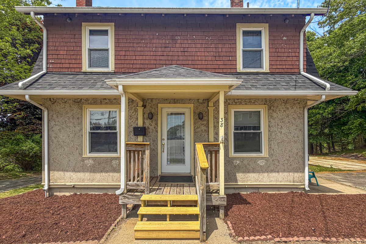 A closer look at the covered porch shows the prominent address markers for simple identification upon arrival. This symmetrical facade highlights the home's unique textures, guiding you toward the side entry path where your vacation begins.