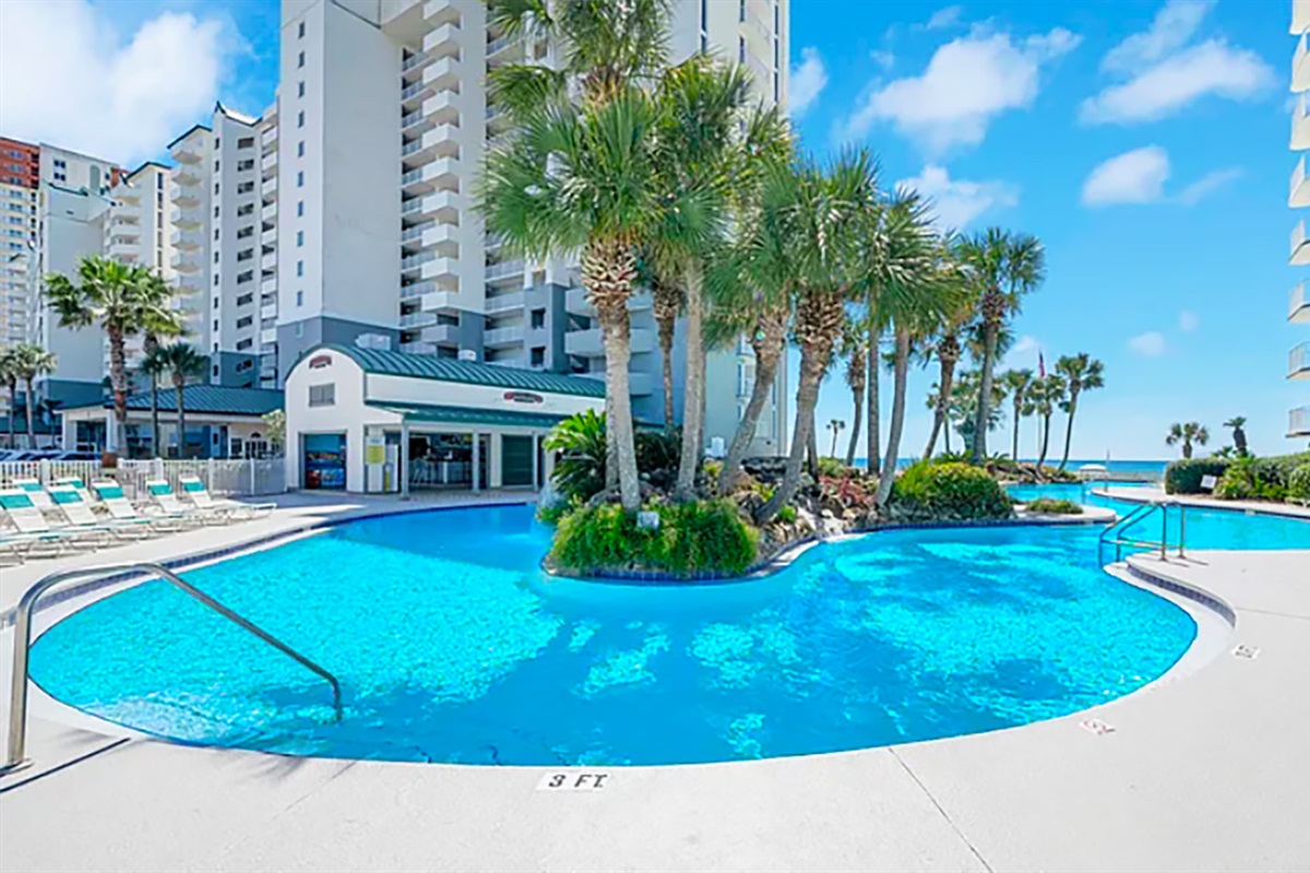 Oversized lagoon pool that is directly overlooking the beach with lush palms and waterfall islands.