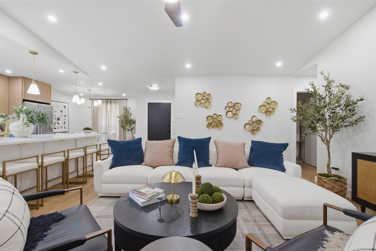 Open Living Room with plush white sectional, vaulted ceiling, and quiet ceiling fan. The bright, airy heart of this Frisco home.