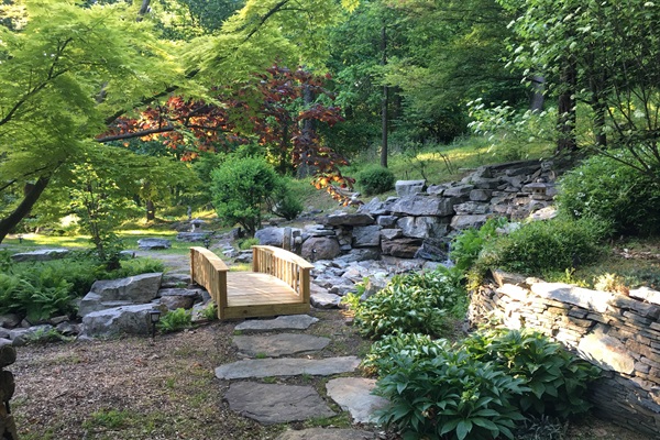 Japanese Bridge (Natural Wood) over waterfall with stone path.